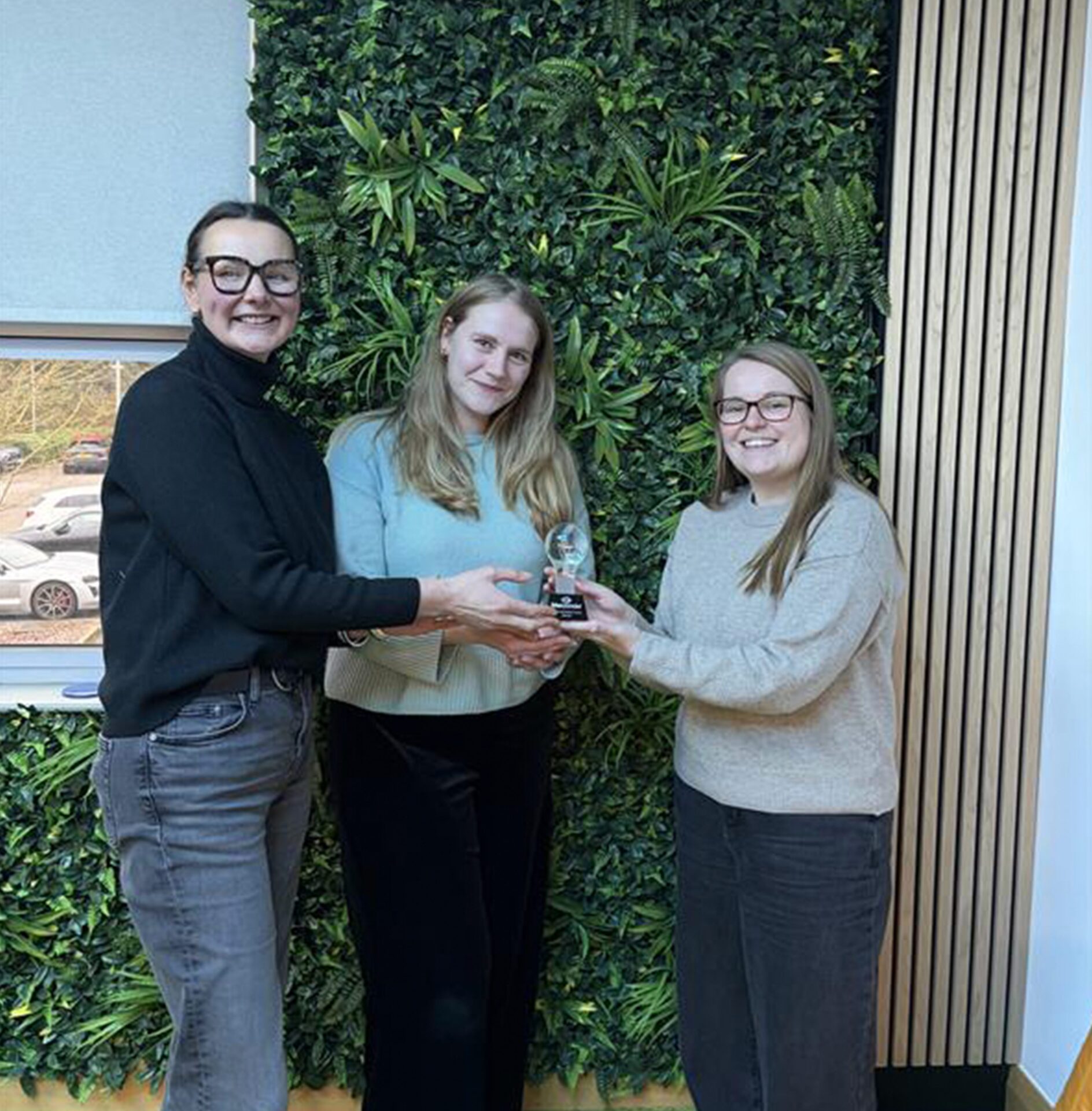 Qual team members, Polly and Anna, collect the Top Client Innovation Award, presented by Hannah Over, Innovation Associate Director.